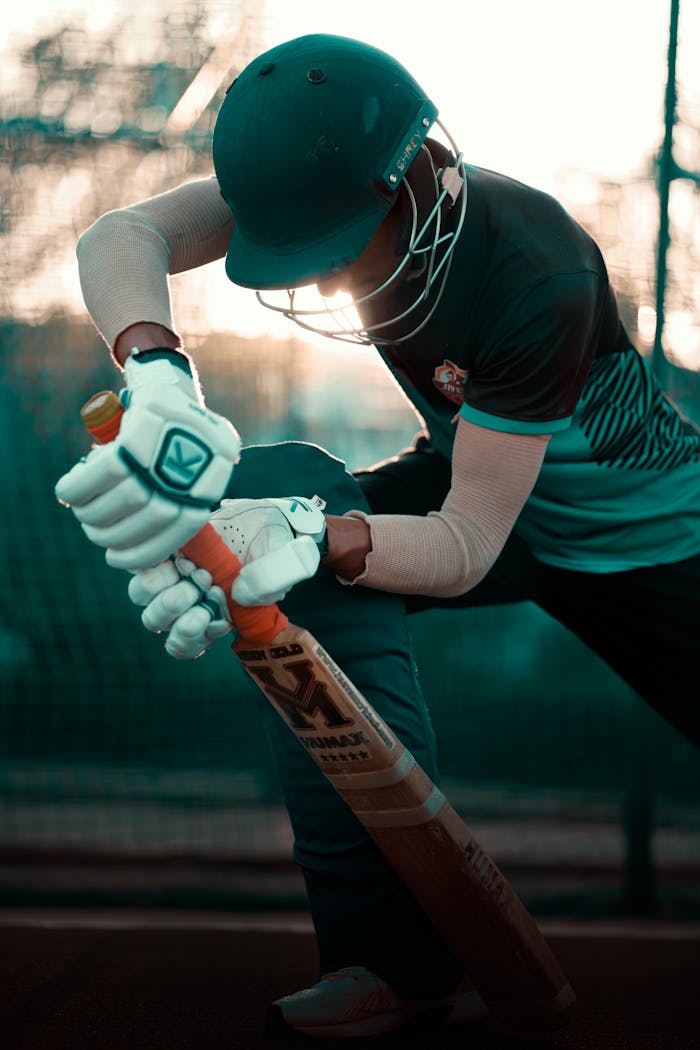Side profile of a cricketer practicing batting technique at sunset.